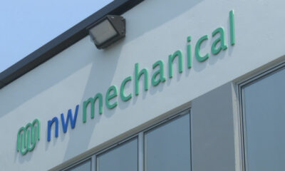Exterior wall sign reading 'nw mechanical' in green and blue letters, with a logo on the left and an outdoor light above.