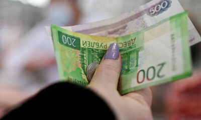 Close-up of a hand with purple nail polish holding and counting Polish zloty banknotes.