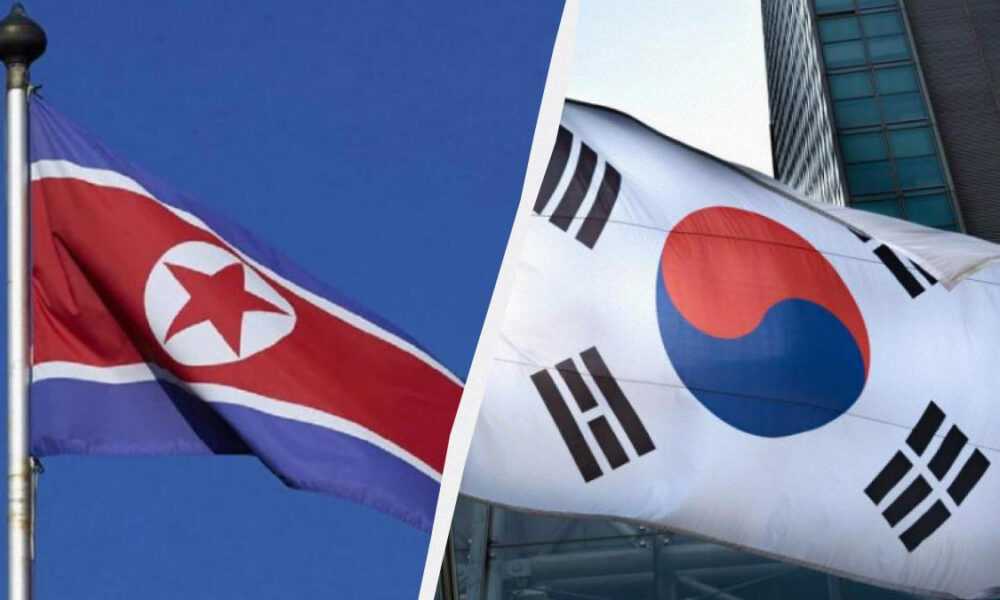 Two Korean flags displayed side by side: left is North Korea, right is South Korea, both waving in the wind.
