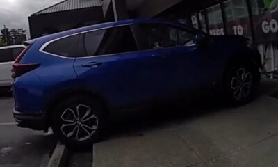 Blue SUV parked on a curbside next to a storefront with its rear hatch open.