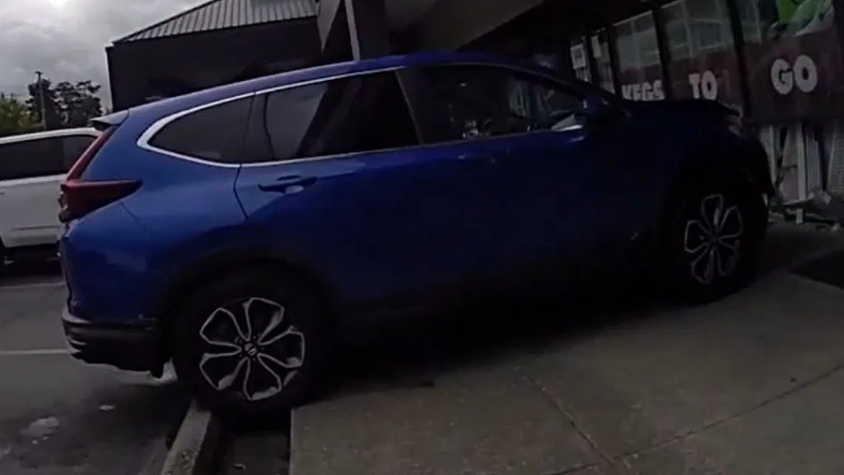 Blue SUV parked on a curbside next to a storefront with its rear hatch open.