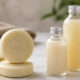 Round cheese wheels stacked on a marble surface with two glass bottles of milk and grains nearby in a kitchen setting.