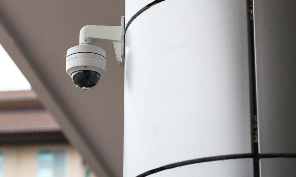 Outdoor dome security camera mounted on a white pillar outside a building