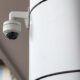 Outdoor dome security camera mounted on a white pillar outside a building