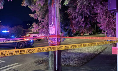 Nighttime police scene with yellow 'POLICE LINE DO NOT CROSS' tape and a patrol car with blue flashing lights.