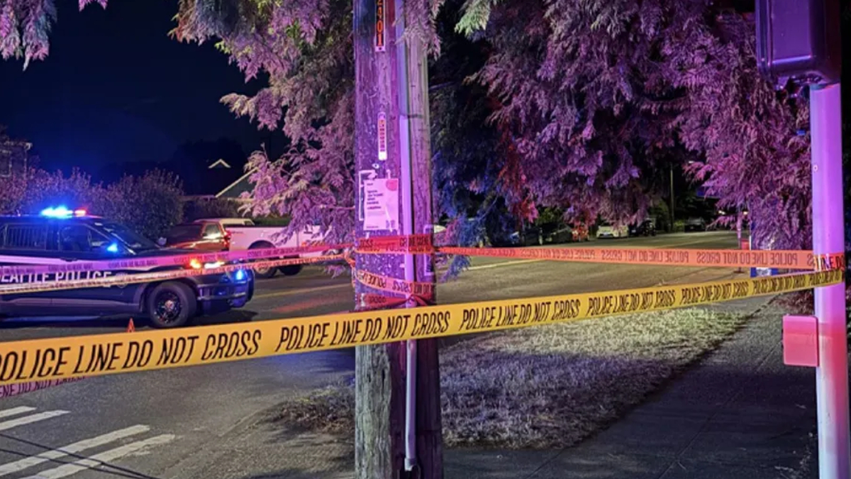 Nighttime police scene with yellow 'POLICE LINE DO NOT CROSS' tape and a patrol car with blue flashing lights.