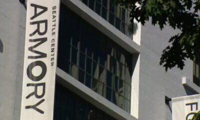 Vertical banner on a gray building reading 'ARMORY' with 'SEATTLE CENTER' text, against windows and tree branches in the foreground.