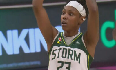 Seattle Storm player #23 with a white headband raises arms in celebration on the basketball court.