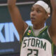 Seattle Storm player #23 with a white headband raises arms in celebration on the basketball court.