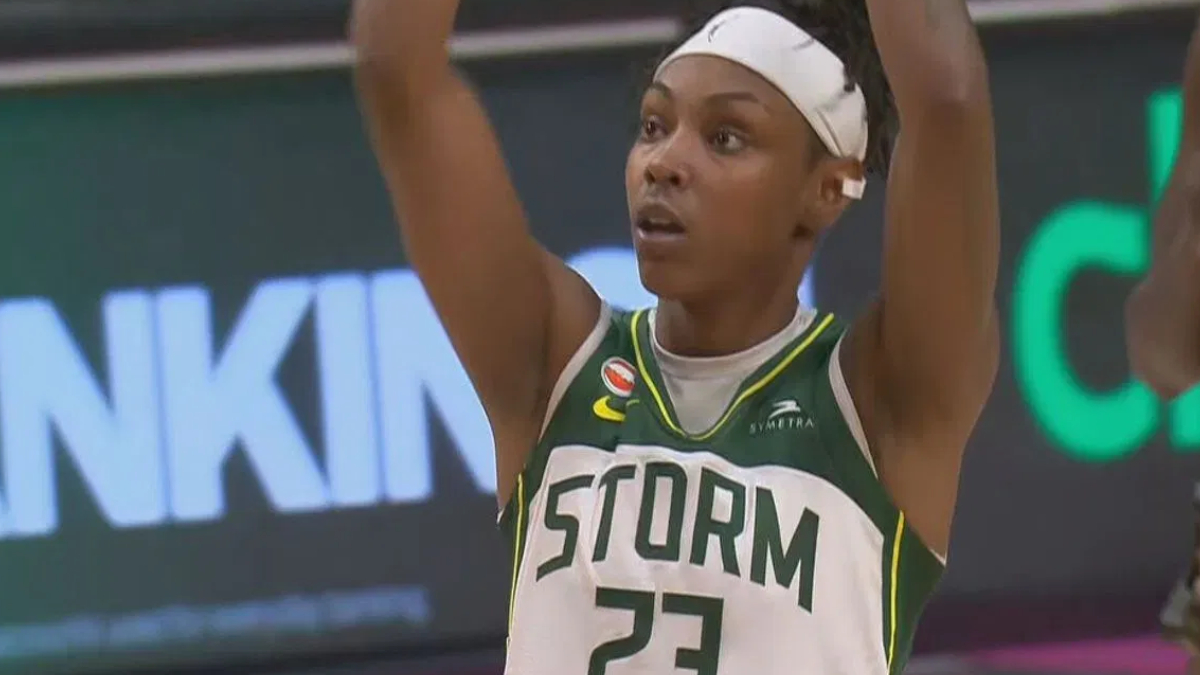Seattle Storm player #23 with a white headband raises arms in celebration on the basketball court.