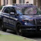 Seattle Police SUV with front bumper guard parked at curb on an urban street; city reflections in windows.