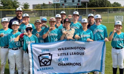 Youth baseball team in teal jerseys posing with banner that reads 'Washington Little League State Champions 2026' on a sunny field.