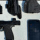 Semi-automatic pistol with a magazine, holster, and a smartphone on a gray surface.
