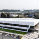 Aerial view of a modern white two-story office building by a waterway, with a parking lot and accessible parking spaces in front.