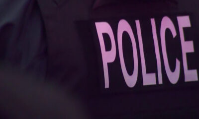 Close-up of a dark police vest with large pink letters spelling POLICE