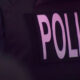 Close-up of a dark police vest with large pink letters spelling POLICE