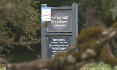 Sign at the entrance of Hockinson Meadows Community Park with 'Welcome' and park regulations text, set among trees.
