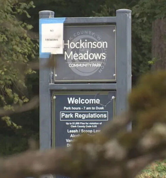 Sign at the entrance of Hockinson Meadows Community Park with 'Welcome' and park regulations text, set among trees.