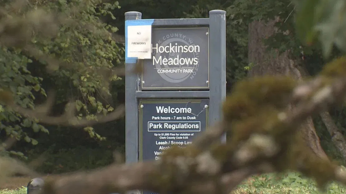 Sign at the entrance of Hockinson Meadows Community Park with 'Welcome' and park regulations text, set among trees.