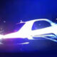 White car involved in a nighttime crash with blue emergency lights flashing in the background.