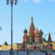 Colorful Saint Basil's Cathedral with onion domes in Red Square, Moscow, crowded plaza in foreground and construction cranes in the background.