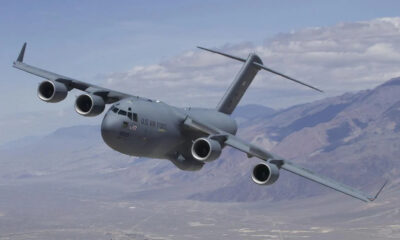 US Air Force C-17 Globemaster III cargo plane flying low over mountains with four engines.