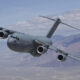US Air Force C-17 Globemaster III cargo plane flying low over mountains with four engines.