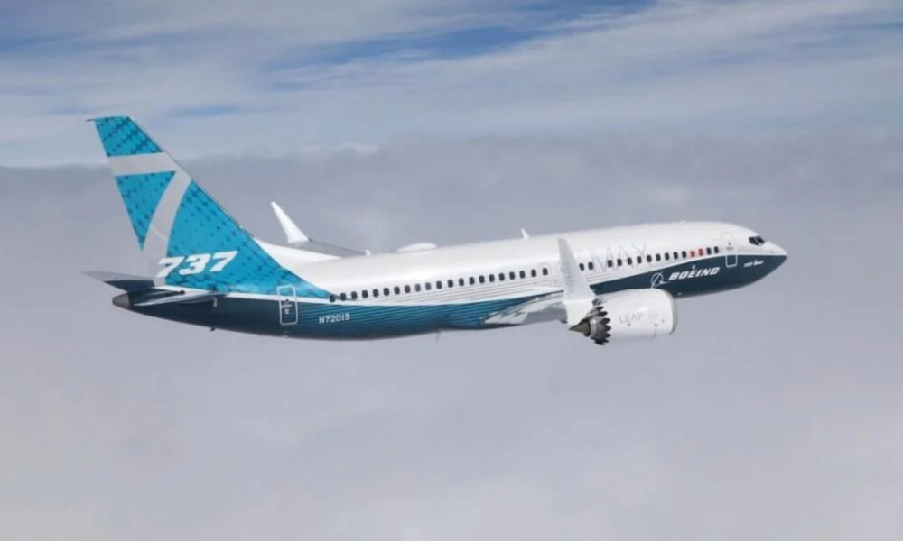 Boeing 737 MAX in flight with blue-turquoise tail and white fuselage, engine visible under the wing.