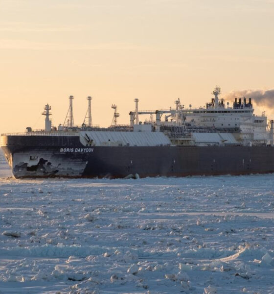 Icebreaker Boris Davydov moving through sea ice at sunset, steam plume trailing from the stack.