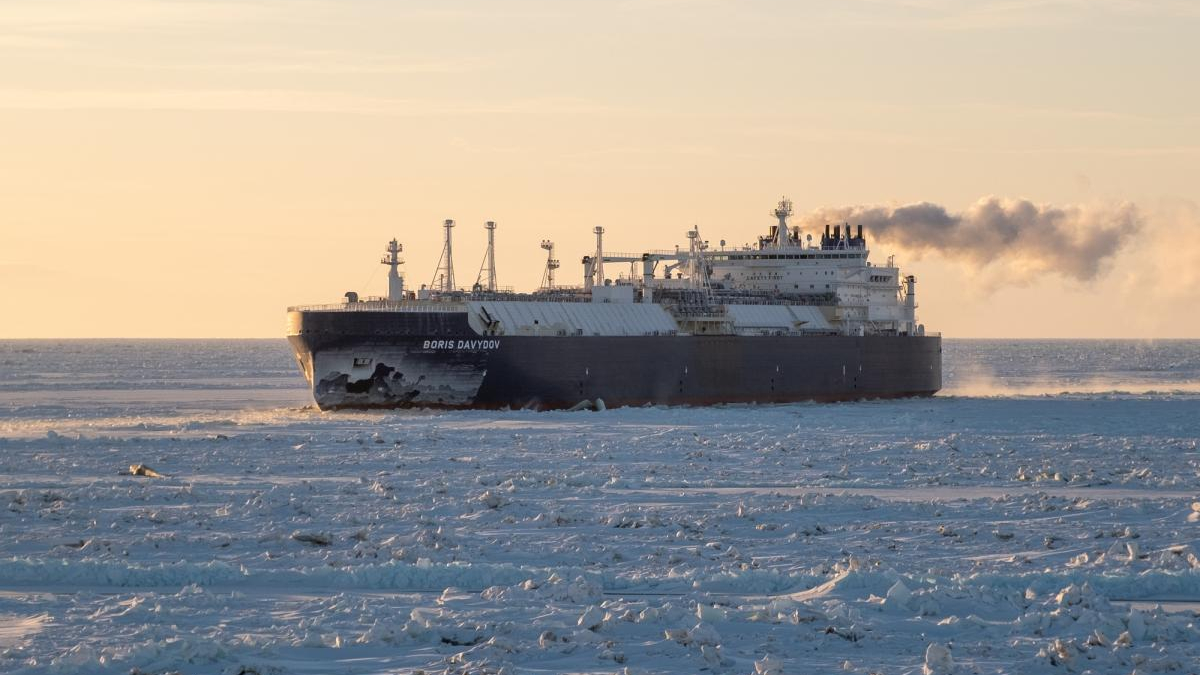 Icebreaker Boris Davydov moving through sea ice at sunset, steam plume trailing from the stack.