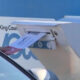 Hand inserting a letter into a blue curbside mailbox labeled King County.