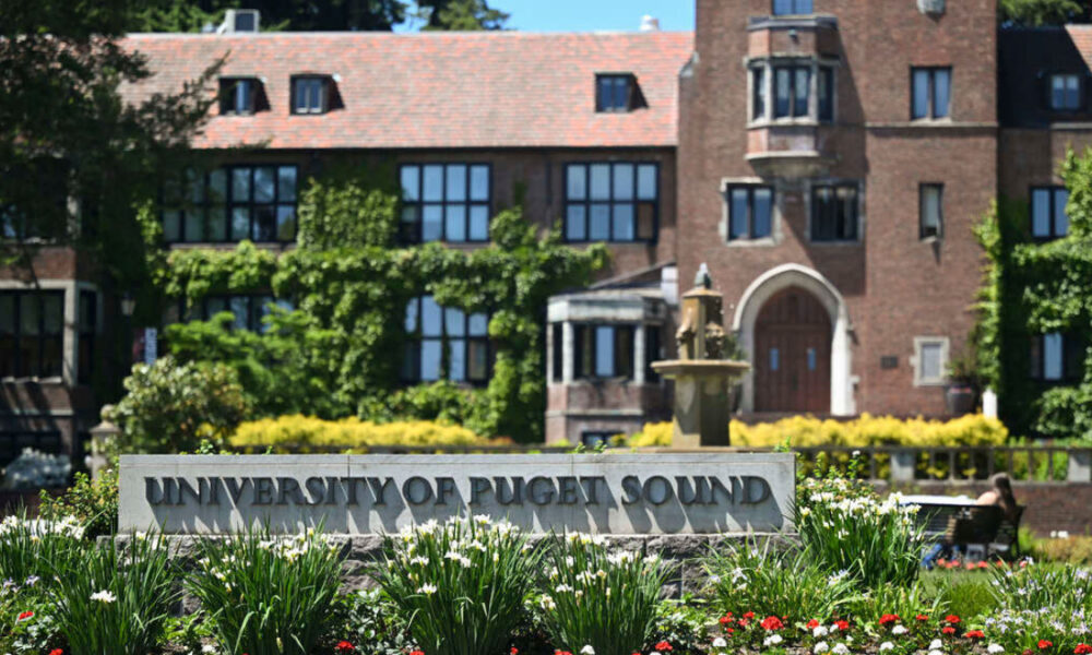 Campus fountain and a brick university building with a sign reading 'University of Puget Sound' in a well-kept garden F