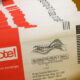 Pile of red and white envelopes labeled 'vote!' for return envelopes, election mail.