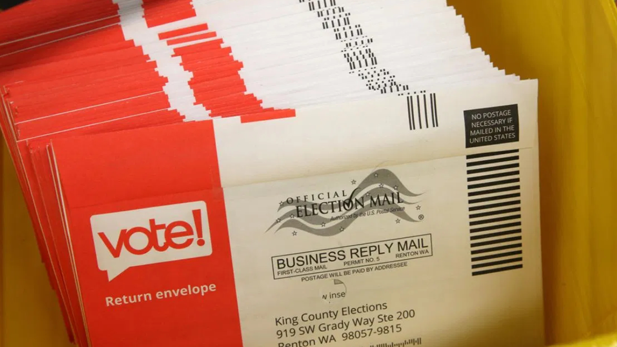 Pile of red and white envelopes labeled 'vote!' for return envelopes, election mail.