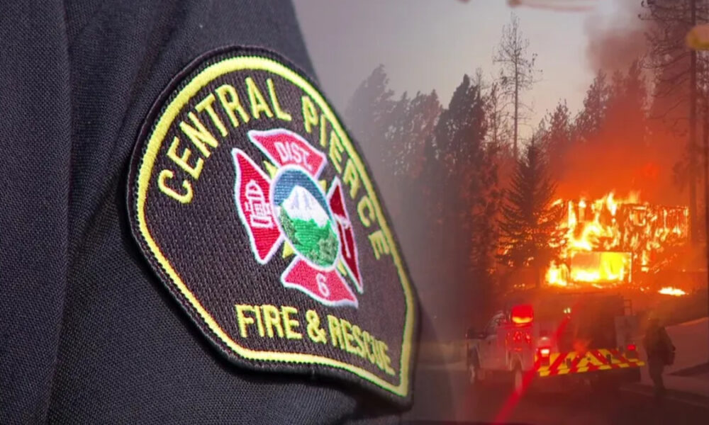 Close-up of a firefighter patch reading 'Central Paciﬁc Fire & Rescue' with a blazing house in the background, flames visible through trees, suggesting an active fire scene.