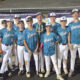 Group of young baseball players in blue uniforms posing with a trophy outdoors at a tournament.