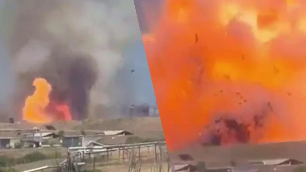 Industrial site on fire with large orange flames and thick black smoke rising from buildings.
