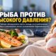 Беременная женщина за столом с приготовленной рыбой, овощами и крупой